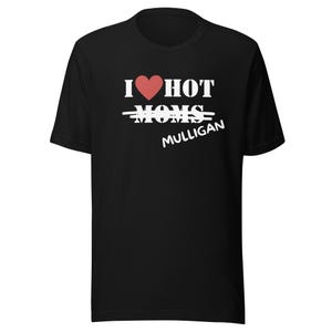 May include: Black t-shirt with the text "I ❤️ HOT" and the word "MOMS" crossed out, replaced by "MULLIGAN" in white. A red heart symbol is above the word "HOT".