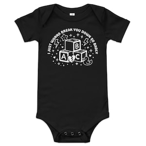 Op de afbeelding: Zwarte babybody met een witte afbeelding. De afbeelding toont drie alfabetblokken met de letters A, B en C, een gebroken hart, een badeend, sterren en de tekst "I just wanna break you down so badly."