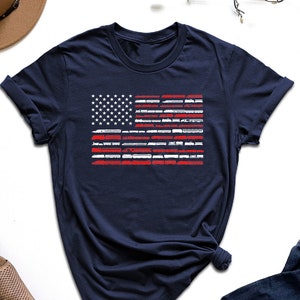 May include: A navy blue t-shirt with a white and red American flag design. The flag is made up of train silhouettes.