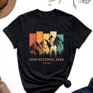 May include: Black t-shirt with a vintage-style graphic of mountains and trees. The text "Zion National Park - Utah -" is printed below the graphic.