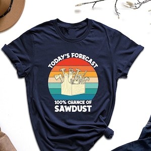 May include: A navy blue t-shirt with a vintage-style graphic of a toolbox full of tools and the text "Today's Forecast 100% Chance of Sawdust".