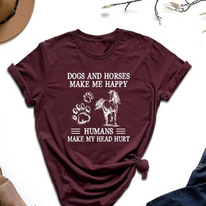 May include: Burgundy t-shirt with white text that reads "Dogs and horses make me happy = humans = make my head hurt". The text is accompanied by a paw print and a horse silhouette.