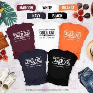 May include: A collection of t-shirts in various colors, including maroon, white, orange, navy, and black. Each shirt features the text "CRITICAL CARE crew ALL DAY EVERY DAY" in a rectangular box. The image includes figs, a hat, and a pair of jeans.