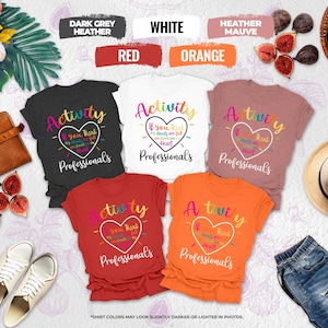 May include: A collection of colorful t-shirts in various hues, including dark grey, white, red, orange, and heather mauve. Each shirt features the text "Activity" with a heart graphic and the phrase "If you think my hands are full you should see my heart Professionals."