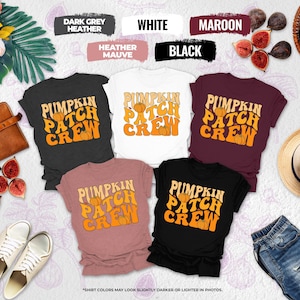 May include: Five short-sleeve t-shirts in dark grey, white, maroon, heather mauve, and black. Each shirt features the text PUMPKIN PATCH CREW in a retro orange font with small pumpkin illustrations. The shirts are arranged in a group display.