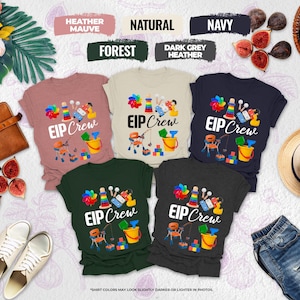 May include: A collection of t-shirts in various colors, including heather mauve, natural, navy, forest, and dark grey heather. Each shirt features a colorful graphic and the text "EIP Crew". The shirts are displayed with accessories like shoes, a hat, and figs.