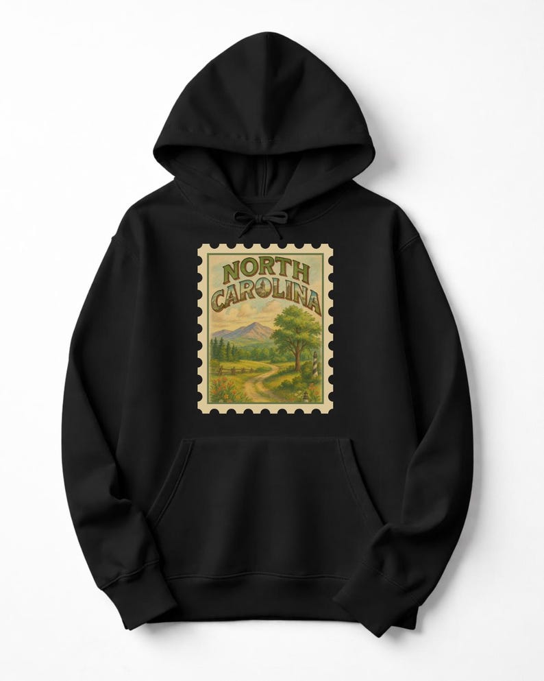 May include: Black hooded sweatshirt featuring a vintage-style North Carolina stamp design. The stamp depicts a scenic landscape with mountains, trees, and a winding road. The text "NORTH CAROLINA" is arched across the top of the stamp.