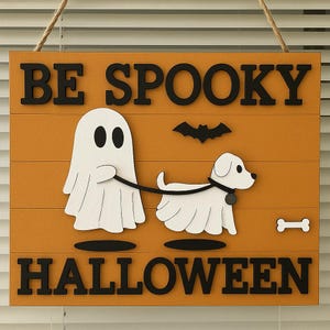 May include: Wooden Halloween sign with the words "BE SPOOKY HALLOWEEN". The sign features a white ghost walking a white dog on a leash, a black bat, and a white bone on an orange background.