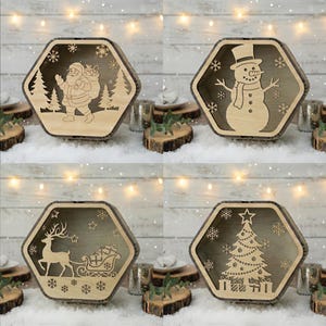 May include: Four wooden, hexagonal Christmas-themed boxes. Each box features a different laser-cut design: Santa Claus, a snowman, a reindeer with a sleigh, and a Christmas tree. The boxes are displayed on a snowy surface.