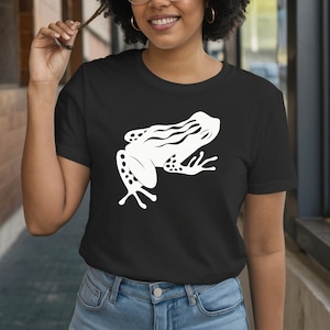 May include: Black t-shirt featuring a white frog graphic. The frog design is a stylized illustration with detailed markings and a unique shape. The shirt is made of a soft material and is suitable for casual wear.
