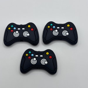 May include: Three black plastic video game controllers with colorful buttons.