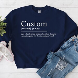 以下が含まれることがあります： カスタム[custom]（名詞）Just a freedom text for describe, jokes, character or anything else. It's about meaning of word.と白文字で書かれたネイビーブルーのスウェットシャツ
