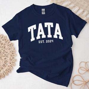 May include: Navy blue t-shirt with white text that reads "TATA EST. 2024".