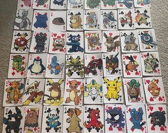 May include: A set of 54 playing cards featuring Pokemon characters. Each card has a different Pokemon illustration, including Pikachu, Charizard, and Squirtle. The cards are standard playing card size and are printed on white card stock.