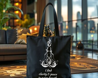 May include: Black canvas tote bag with a white design of a person in a yoga pose with flames above their head. The text "I find clarity & peace in every breath." is printed below the design.
