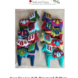 May include: A collection of eight handcrafted felt Dala horse ornaments in various colors including green, blue, red, purple, and yellow. Each horse features decorative stitched patterns, contrasting saddles, and white embroidery details. The image includes the text Pearl and Poppy, Scandinavian Felt Ornament Pattern, and Dala Horse.