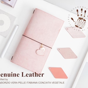 K&ouml;nnte beinhalten: Ein rosafarbenes Lederjournal mit einem herzf&ouml;rmigen Anh&auml;nger und dem Text "Genuine Leather Certified by CONSORZIO VERA PELLE ITABIANA CONCIATA VEGETALE" unten aufgedruckt.