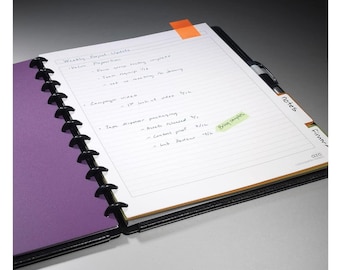 May include: A purple and black notebook with a white page open. The page has handwritten notes about a weekly project update. The notes include the words "Value Proposition" and "Campaign Video".