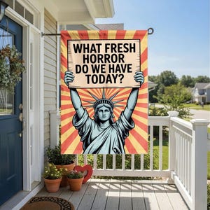 May include: A decorative garden flag featuring the Statue of Liberty holding a sign with the text "WHAT FRESH HORROR DO WE HAVE TODAY?" The flag has a red and yellow sunburst background.