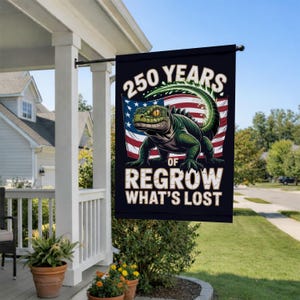 May include: A black outdoor flag with the text "250 YEARS OF REGROW WHAT'S LOST" and a green iguana illustration in front of an American flag. The flag is hanging on a porch.