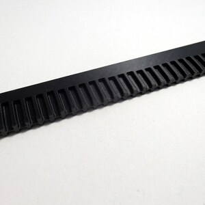 May include: A black plastic comb with a long, thin handle and a row of teeth along the top.
