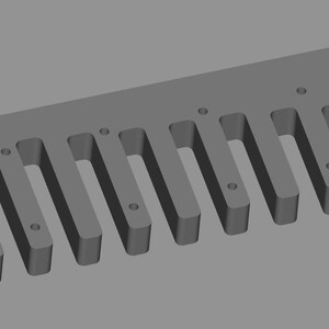May include: A gray, rectangular woodworking jig with evenly spaced, rectangular slots. The jig has a series of small, circular holes along its surface and at each end. The tool is designed for precise joinery and woodworking projects.