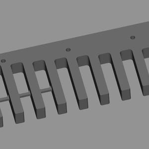 May include: A gray, rectangular woodworking jig with evenly spaced slots and holes. The jig appears to be made of a solid material and is designed for precise cuts in wood. The design suggests it is used for creating joints.