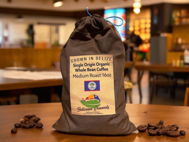 May include: A brown burlap bag filled with whole bean coffee. The bag has a label that says "Grown in Belize Single Origin Organic Whole Bean Coffee Medium Roast 16oz". The label also features the Belizean flag and the logo for Belizean Grounds.