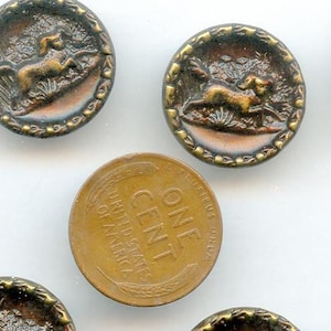 May include: A collection of vintage buttons with a detailed design. Each button features a relief image of a dog in a natural setting, surrounded by a decorative border. The buttons have a metallic finish with shades of brown and gold.