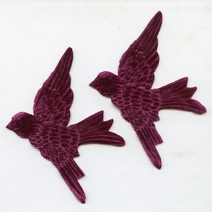 Peut inclure: Deux appliqués d'oiseaux en velours bordeaux. Les oiseaux sont en vol, avec des ailes et des plumes de queue détaillées. Le tissu en peluche a un aspect texturé, et les oiseaux sont posés sur un fond blanc. Ces appliqués décoratifs sont parfaits pour l'artisanat et l'embellissement.