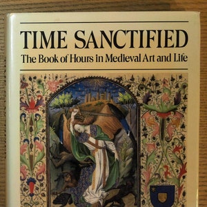 Puede incluir: Un libro de tapa dura titulado "TIME SANCTIFIED" con el subt&iacute;tulo "The Book of Hours in Medieval Art and Life". La portada presenta una ilustraci&oacute;n medieval con figuras, bordes florales y un escudo de armas. El libro est&aacute; sobre una superficie de madera.