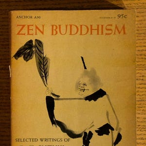 May include: Vintage paperback book titled "Zen Buddhism" by D.T. Suzuki, edited by William Barrett. The cover features an illustration of a figure holding a feather. The book is a Doubleday Anchor Book.