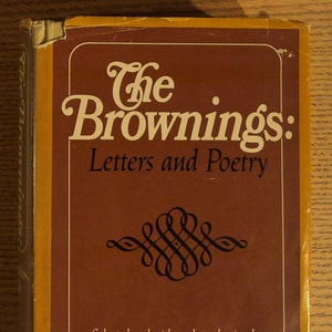 May include: A vintage book titled "The Brownings: Letters and Poetry" with a brown cover and gold trim. The title is in white, stylized lettering. The book cover also features decorative scrollwork and the author's name.