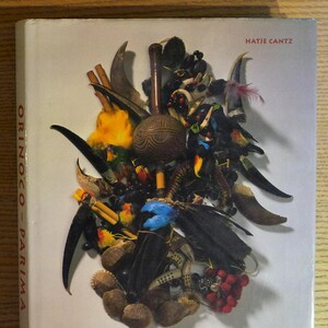 May include: A hardcover book titled "ORINOCO - PARIMA" by Hatje Cantz. The cover features a collage of natural elements in various colors, including feathers, seeds, and wooden objects. The subtitle reads "INDIAN SOCIETIES IN VENEZUELA - The Cisneros Collection."