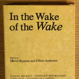 May include: A yellow book cover with the title "In the Wake of the Wake" and a list of authors including Samuel Beckett, Christine Brooke-Rose, John Cage, Augusto de Campos, and more.