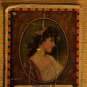 May include: Vintage advertisement card featuring an oval portrait of a woman in profile, set against a dark brown background. The card has a decorative border and includes text for "HARRY WARE, Dealer In COAL & WOOD, EXPRESSING, 919 South Western Avenue, Chicago."