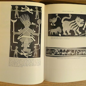 May include: Open book with pages featuring black and white illustrations. One page shows a central figure with outstretched arms, surrounded by smaller figures. The other page displays animal-like figures and a decorative border.