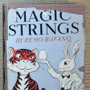 May include: Vintage book cover for "Magic Strings" by Remo Bufano. The cover features a cartoon tiger and a rabbit in a tuxedo, with the rabbit holding an egg. The title is in large, bold letters.