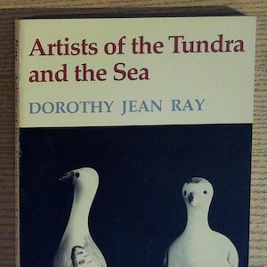 May include: Book cover with the title "Artists of the Tundra and the Sea" by Dorothy Jean Ray. The cover features a black and white photo of two ceramic birds.