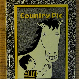 May include: A book cover with a yellow background and black border. The title "Country Pie" is in large, bold, yellow letters. A black and white illustration of a horse and a child is in the center. The author's name, "Frank Asch", is in black letters at the bottom.