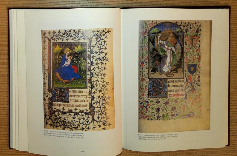 Puede incluir: Libro abierto con dos p&aacute;ginas de manuscritos iluminados. La p&aacute;gina izquierda presenta a la Virgen Mar&iacute;a y el ni&ntilde;o con una t&uacute;nica azul, rodeados de estrellas doradas y bordes florales. La p&aacute;gina derecha muestra una escena religiosa con figuras y dise&ntilde;os florales.