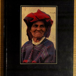 May include: A book cover with a portrait of a woman in traditional Guatemalan attire. She wears a red head covering, a beaded necklace, and a patterned shawl. The title "Indian Costumes from Guatemala" is printed in gold lettering.