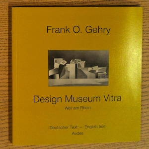 May include: A yellow book cover with the title "Frank O. Gehry" and "Design Museum Vitra" in black text. A black and white image of a building is in the center. The text "Deutscher Text - English text" is at the bottom.