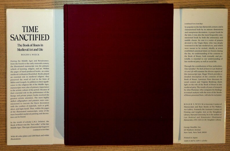 Puede incluir: Un libro de tapa dura titulado "Time Sanctified: The Book of Hours in Medieval Art and Life" de Roger S. Wieck. El libro tiene una cubierta de color burdeos oscuro y p&aacute;ginas blancas con texto. El libro est&aacute; abierto, revelando el t&iacute;tulo y el autor.