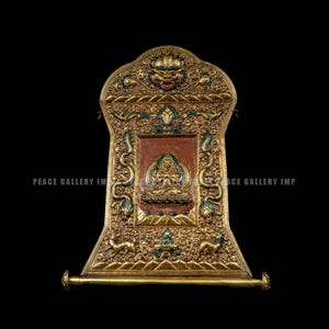 May include: Ornate gold-colored religious artifact with intricate carvings and green accents. Features a central panel with a seated figure and scroll-like base. The text "PEACE GALLERY IMP" is visible.