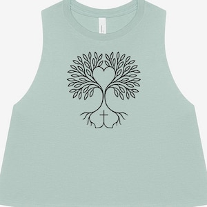 May include: A light green crop top featuring a black tree design. The tree has a heart-shaped crown and a cross-like base. The sleeveless top is made of a soft material, perfect for casual wear.