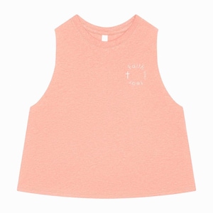 May include: A peach-colored sleeveless crop top with a round neckline. The top features a white circular graphic with a cross and the words "Faith over fear". The fabric has a textured appearance.