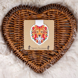May include: A magnetic bookmark featuring a colorful illustration of a lion's head with a lamb inside. The bookmark is on a brown card with the text "Magnetic Bookmark" printed on it.