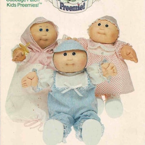 May include: A vintage sewing pattern for Cabbage Patch Kids Preemie dolls. The pattern includes instructions for making clothes for three Cabbage Patch Kids dolls. The dolls are wearing a pink dress, a blue and white striped outfit, and a pink and white dress. The pattern is titled "Cabbage Patch Kids" and the number 6981 is printed in the top right corner.