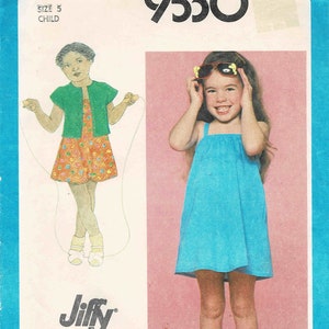 May include: Simplicity sewing pattern number 9530 for a child's dress. The pattern includes two styles: a blue sleeveless dress and a green cardigan with a floral print dress. The pattern is labeled "Jiffy" and is for size 5.